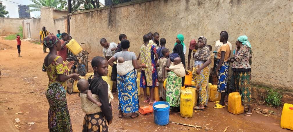 Community members line up to fill water containers